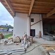 Rohbau mit Holzbalken und Baumaterialien auf dem Boden.