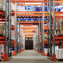 Lagerhalle mit Regalen, Paletten und Verpackungsmaterial.