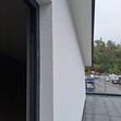 Facciata bianca dell’edificio con telaio scuro della finestra e bordo del tetto piano.