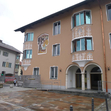 Gebäude mit rosafarbener, teilweise bemalter Fassade und Eingangsbogen.