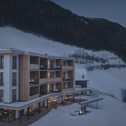 Modernes Hotelgebäude in verschneiter Berglandschaft.