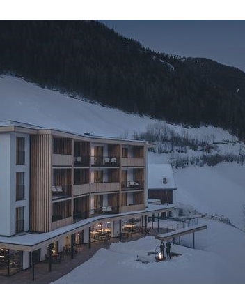 Edificio alberghiero moderno in un paesaggio montano innevato.