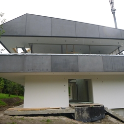 Modernes weißes Haus mit grauem Dach und Balkon.