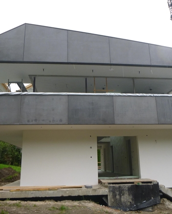 Casa moderna bianca con tetto grigio e balcone.