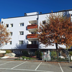 Edificio moderno con facciata chiara; davanti, attrezzature da cantiere e parcheggi.