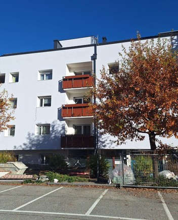 Edificio moderno con facciata chiara; davanti, attrezzature da cantiere e parcheggi.